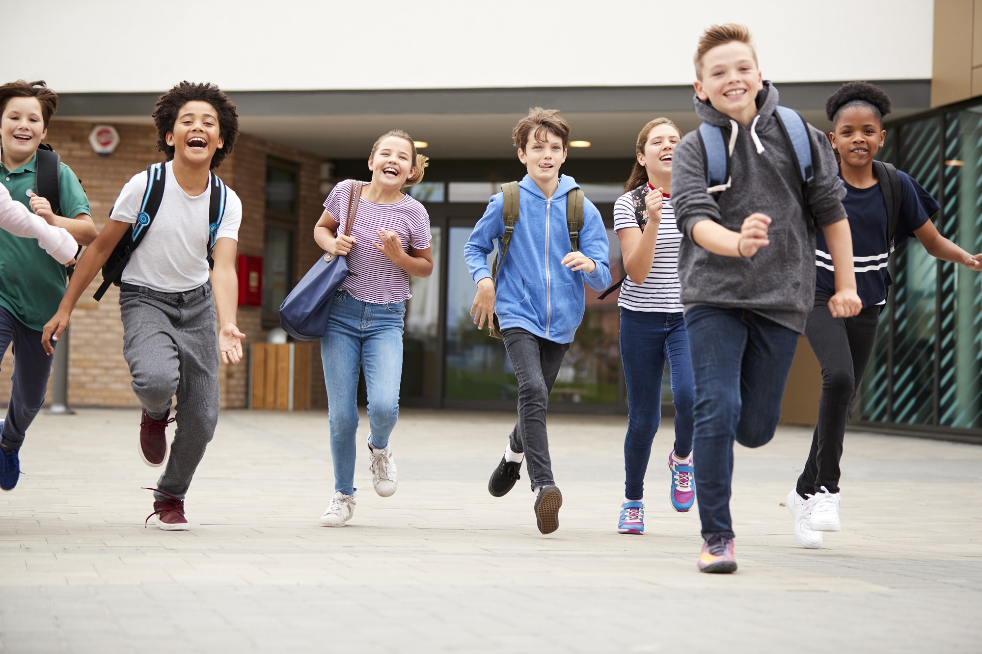 Schüler laufen lachend aus Schulgebäude. Schüler laufen lachend aus Schulgebäude.
