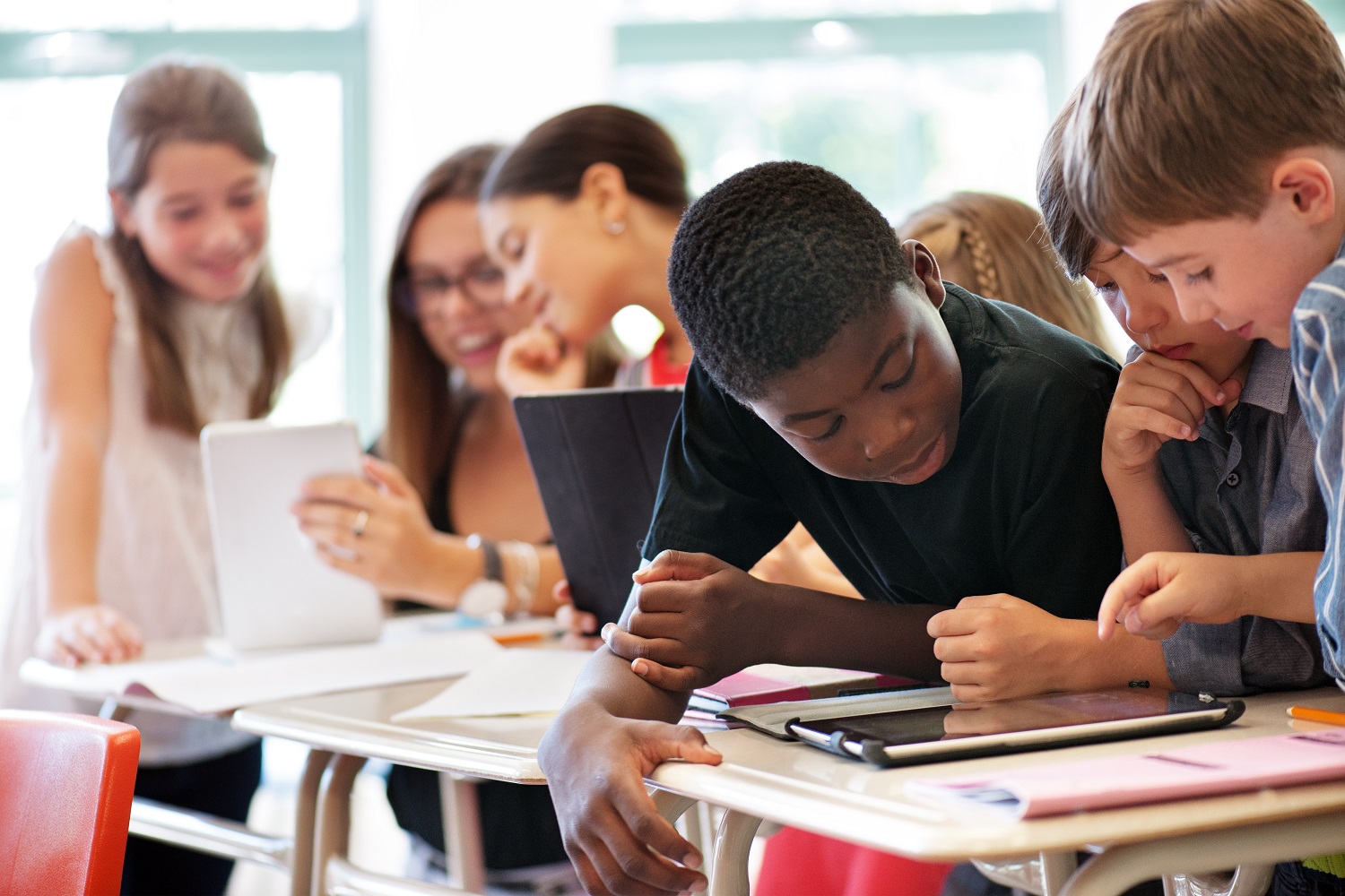 Schülerinnen und Schüler blicken auf Tablets, die vor ihnen auf dem Tisch liegen. Schülerinnen und Schüler blicken auf Tablets, die vor ihnen auf dem Tisch liegen.