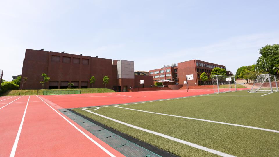 Man sieht den Sportplatz der Deutschen Schule Tokyo Yokohama, das Schulgelände im Hintergrund
