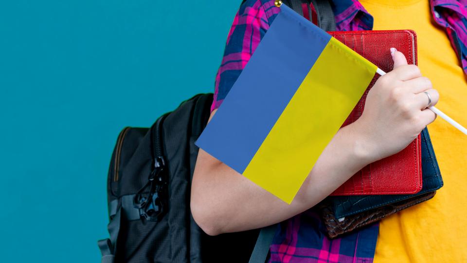Schülerin mit Rucksack und Ukraine-Flagge
