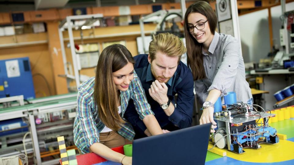 Drei Schülerinnen und Schüler arbeiten in einer Robotikwerkstatt.