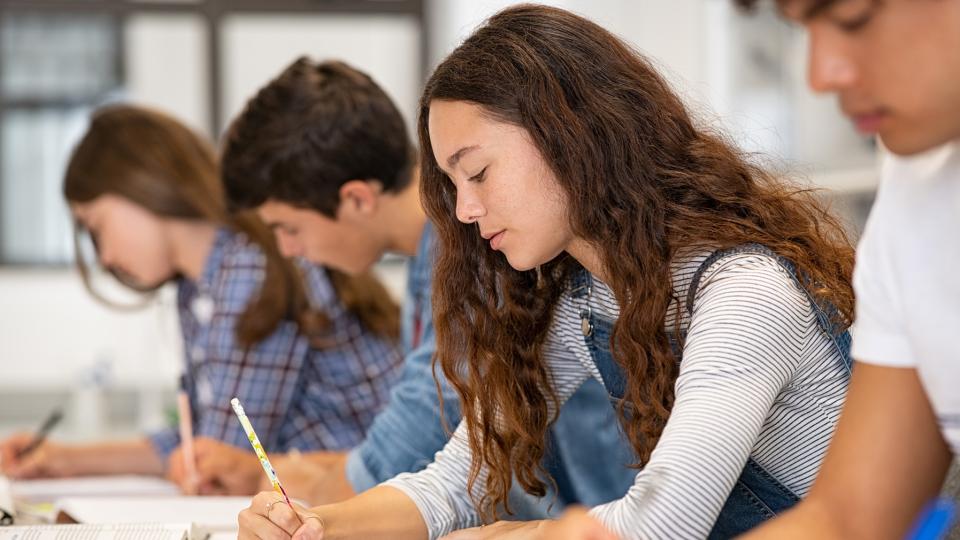 Schülerinnen und Schüler sind in eine schriftliche Prüfung vertieft.