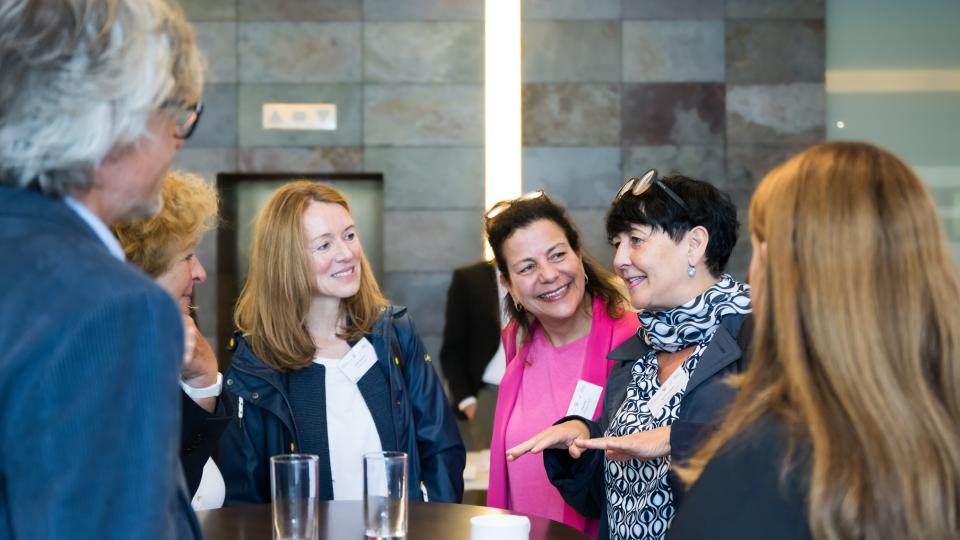 Teilnehmende der Auftaktkonferenz zum Startchancen-Programm an einem Stehtisch vor der Veranstaltungshalle