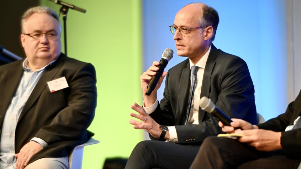 Staatssekretär Dr. Urban Mauer spricht im Rahmen einer Gesprächsrunde auf dem Podium. 