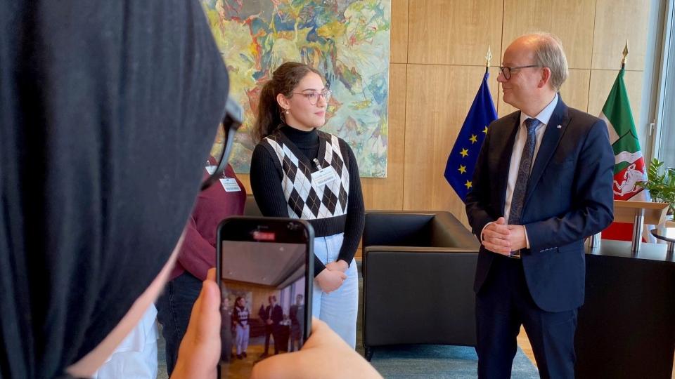 Eine Schülerin fotografiert eine weitere Schülerin und Landtagspräsident Kuper im Landtag.