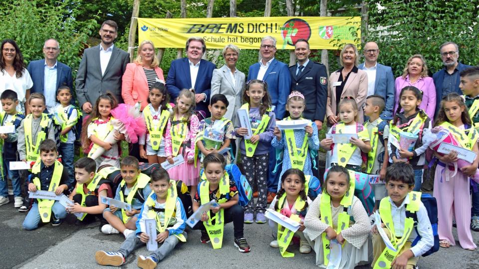 Gruppenbild von Ministerin Dorothee Feller mit Vertreterinnen und Vertretern der Landesverkehrswacht und Schülerinnen und Schülern, im Hintergrund ein Banner mit der Aufschrift "Brems Dich! Schule hat begonnen!"