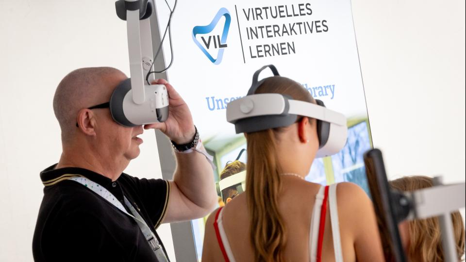 Zwei Gäste testen beim Besuch des Schulministeriums Standes VR-Brillen.