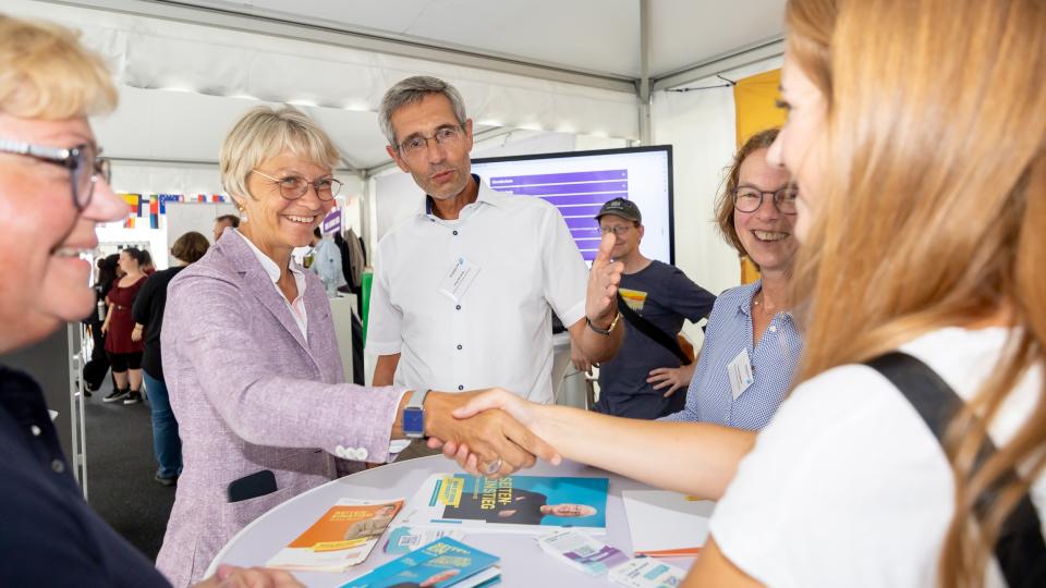 Schulministerin Dorothee Feller begrüßt am Samstagnachmittag eine Besucherin am Stand des Schulministeriums.