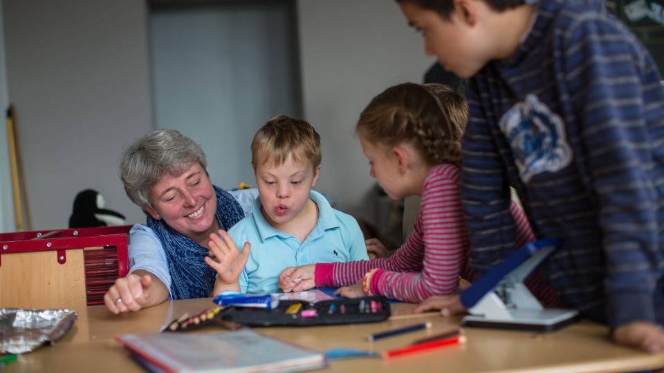 Lehrerin und Kinder mit und ohne Behinderung in Unterrichtssituation Lehrerin und Kinder mit und ohne Behinderung in Unterrichtssituation