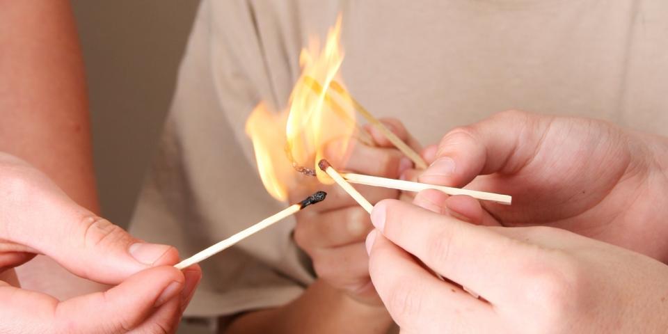 Mehrere Hände halten brennende Streichhölzer zusammen, zu erkennen ist in der Mitte nur ein Kind, das ebenfalls ein Streichholz in die große Flamme streckt.  Mehrere Hände halten brennende Streichhölzer zusammen, zu erkennen ist in der Mitte nur ein Kind, das ebenfalls ein Streichholz in die große Flamme streckt.