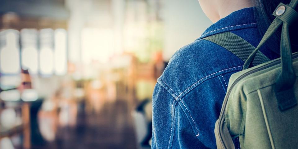 Schülerin mit Rucksack schaut auf einen leeren Schulflur Schülerin mit Rucksack schaut auf einen leeren Schulflur
