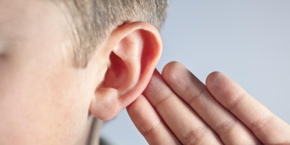 Nahaufnahme eines Kindes, das sich die Hand hinter das Ohr hält. Nahaufnahme eines Kindes, das sich die Hand hinter das Ohr hält.