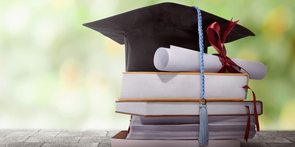 Ein Doktorhut liegt auf einem Stapel Bücher  Ein Doktorhut liegt auf einem Stapel Bücher