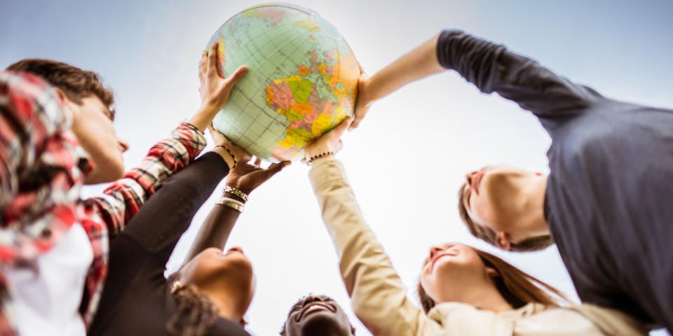 Froschperspektive: Fünf Menschen halten einen Globus in die Höhe. Froschperspektive: Fünf Menschen halten einen Globus in die Höhe.