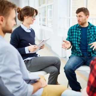 Beratungssituation, mehrere Personen sitzen in einem Kreis und sprechen miteinander.