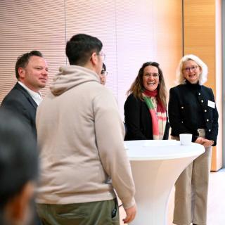 Ein Schüler unterhält sich mit Ministerin Feller und weiteren Mitarbeitenden des MSB.