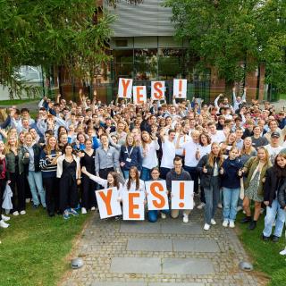 Die Teilnehmenden am Finale des Wettbewerbs Young Economic Solutions 2023 stehen beieinander und halten Schilder mit der Aufschrift YES! in die Höhe.